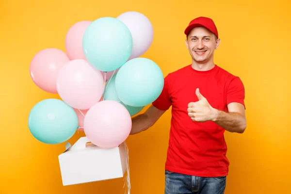 Man giving food order cake box isolated on yellow background. Male employee courier in red cap t-shirt hold colorful air balloons, dessert in empty cardboard box. Delivery service concept. Copy space