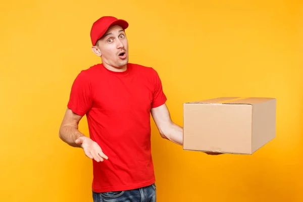 送人在红色制服被隔绝在黄色橙色背景 专业男性员工信使或经销商在帽 T恤上持有空纸板箱 接收包服务概念 — 图库照片