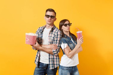 Genç çift kadın adam 3d gözlük film film izlerken patlamış mısır plastik bardak soda kova tutarak tarihte söz konusu veya sarı arka plan üzerinde katlanmış elele cola izole. Sinema duygular