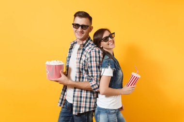 3d gözlük kova patlamış mısır bardak kola veya kola arka arkaya diğer izole sarı arka plan üzerinde ayakta tutan tarihi film film izlerken içinde genç gülümseyen iki kadın adam. Sinema duygular