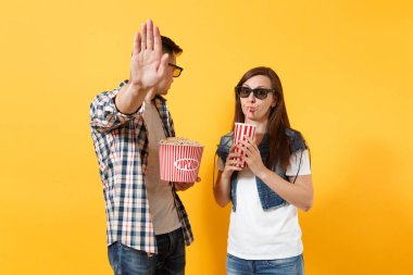 Genç çift kadın adam 3d gözlük tutan kova patlamış mısır bardak soda veya stop jest sarı arka plan üzerinde izole palm ile gösterilen cola tarihi film film izlerken içinde üzmek. Sinema duygular