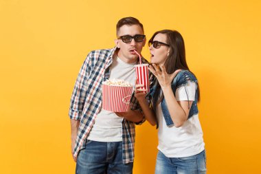 Genç çift kadın adam 3d gözlük kova patlamış mısır kola veya kola plastik kap üzerinde sarı arka plan izole içme tutan tarihi film film izlerken rahatsız edilmiş. Duygu sinema kavram