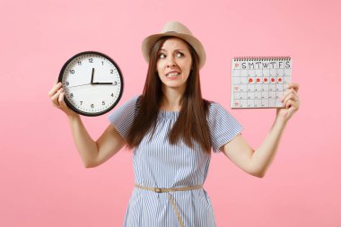 Yuvarlak saat, pembe eğilimleri arka plan üzerinde izole adet gün kontrol etmek için dönemleri takvim tutan mavi elbiseli şok karışık üzgün kadın. Tıbbi jinekolojik kavramı. Kopya alanı