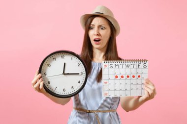 Yuvarlak saat, pembe eğilimleri arka plan üzerinde izole adet gün kontrol etmek için dönemleri takvim tutan mavi elbiseli şok karışık üzgün kadın. Tıbbi jinekolojik kavramı. Kopya alanı