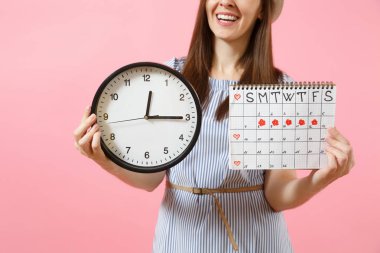 Yuvarlak saat, pembe eğilimleri arka plan üzerinde izole adet gün kontrol etmek için dönemleri takvim tutan mavi elbiseli kadın kırpılmış fotoğrafı. Tıp, sağlık, jinekolojik kavramı. Kopya alanı