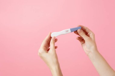 Erkek yakından eller hamilelik testi pembe eğilimleri arka plan üzerinde izole tutar. Tıbbi sağlık jinekolojik, gebelik doğurganlık hamile insanlar kavramı. Kimse. Kopyalama alanı reklam