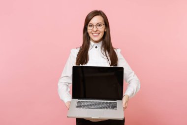 Dizüstü pc bilgisayar, pembe arka plan izole boş boş ekran ile tutarak gözlüklü genç başarılı iş kadını. Bayan patron. Başarı kariyer servet kavramı. Kopya alanı reklam için