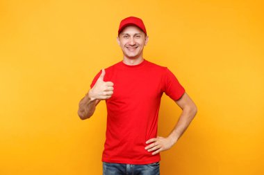 Teslimatçı sarı turuncu arka plan üzerinde izole kırmızı üniforma. Profesyonel gülümseyen erkek çalışan şapkalı, kurye veya satıcı gösteren olarak çalışma t-shirt jest başparmak. Hizmet anlayışı.
