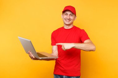 Sarı turuncu arka plan üzerinde izole teslimatçı. Profesyonel erkek çalışan kurye kırmızı şapkalı, dizüstü pc bilgisayarda yazarak çalışma tutan t-shirt. Hizmet anlayışı. Kopya alanı reklam için