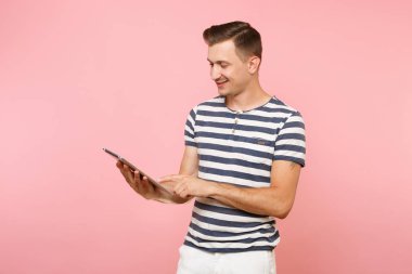 Tablet pc bilgisayarınıza çalışma çizgili tişört giyen Kullanıcı genç adam portresi gidişli pastel pembe arka plan üzerinde izole. İnsanlar samimi duygular yaşam tarzı kavramı. Alan kopya alanı üzerinde reklam