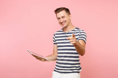 Tablet pc bilgisayarınıza çalışma çizgili tişört giyen Kullanıcı genç adam portresi gidişli pastel pembe arka plan üzerinde izole. İnsanlar samimi duygular yaşam tarzı kavramı. Alan kopya alanı üzerinde reklam