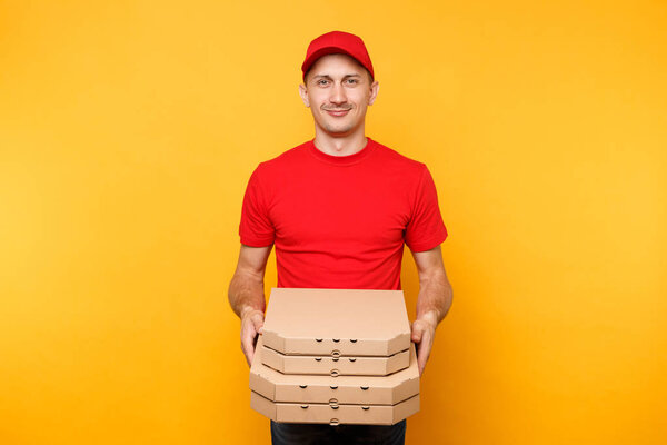 Delivery man in red cap, t-shirt giving food order pizza boxes isolated on yellow background. Male employee pizzaman or courier in uniform holding italian pizza in cardboard flatbox. Service concept