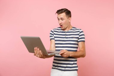Dizüstü bilgisayar, eğilimleri pastel pembe arka plan üzerinde izole kopya alanı üzerinde tişört giyen yakışıklı genç adam portresi çizgili. İnsanlar samimi duygular yaşam tarzı kavramı. Reklam alanı