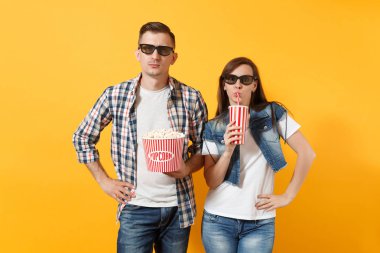 Genç kadın çift ve 3d gözlük kova patlamış mısır ve kola veya kola sarı arka plan üzerinde izole plastik bardak tutan tarihi film film izlerken erkekte söz konusu. Sinema kavramı duygular