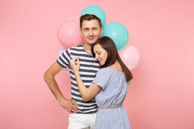 Aşık genç mutlu gülümseyen çift portresi. Kadın bir adam göğüs kutluyor Doğum günü tatile yağsız parti renkli hava balonları pastel pembe zemin üzerine. İnsanlar samimi duygular kavramı
