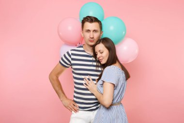 Aşık genç mutlu gülümseyen çift portresi. Kadın bir adam göğüs kutluyor Doğum günü tatile yağsız parti renkli hava balonları pastel pembe zemin üzerine. İnsanlar samimi duygular kavramı