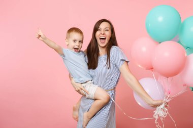 Genç mutlu aile, Anne tut kollarında, portresi iyi eğlenceler çocuk çocuk evlat bebek çocuk, Doğum günü kutluyor sarılmak, tatil parti renkli hava balonları ile pembe arka plan üzerinde. Samimi duygular kavramı