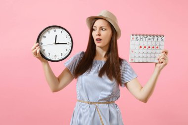 Yuvarlak saat, pembe eğilimleri arka plan üzerinde izole adet gün kontrol etmek için dönemleri takvim tutan mavi elbiseli şok karışık üzgün kadın. Tıbbi jinekolojik kavramı. Kopya alanı