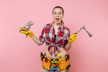 Giyen ekose gömlek, kot şort, kit araçları kemer farklı enstrümanlar spanner, pembe arka plan izole dolu güçlü genç tamirci kadın. Kadın erkek iş. Yenileme ve işgal kavramı
