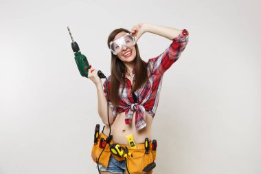 Güçlü genç enerji ev erkeği kadın ekose üst gömlek kot kemer koruyucu gözlük araçların tam tutun beyaz arka plan üzerinde izole elektrikli matkap Seti Araçları şort. Kadın erkek çalışmalarında