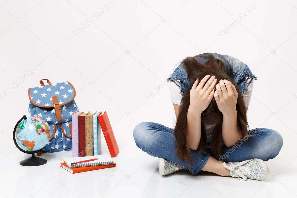 Portrait of young upset depressive woman student leaning clinging to head, sitting looking on globe, backpack, school books isolated on white background. Education in high school university college