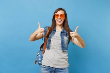 Çok komik kadın sırt çantası giyiyor ile turuncu öğrenci kalp gözlük başparmak yukarıya üstünde izole mavi arka plan gösteren gülen genç portresi. Üniversitesi'nde eğitim. Kopya alanı reklam için