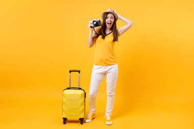 Heyecanlı turist kadın yaz rahat kıyafetler, çanta, sarı zemin üzerine izole retro vintage fotoğraf makinesi ile şapka. Hafta sonu kaçış üzerinde seyahat için yurt dişi. Hava uçuş kavramı