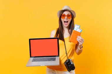 İzole sarı turuncu arka plan üzerine boş siyah Boþ ekran passport biletleri ile dizüstü pc bilgisayar tutan turist kadın. Hafta sonu kaçış üzerinde seyahat için yurt dişi. Hava uçuş kavramı