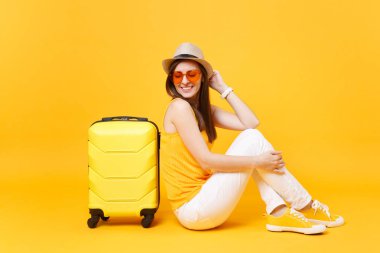 Seyahat etmek turist kadın yaz rahat kıyafetler, sarı turuncu arka plan üzerinde izole çanta şapka sit. Hafta sonu kaçış üzerinde seyahat için yurt kadın yolcu. Hava yolculuğu kavramı