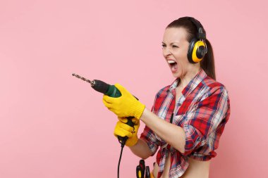 Enerji seksi tamirci kadın eldiven, gürültü yalıtımlı kulaklıklar, Seti Araçları, pembe arka plan izole elektrikli matkap tutan araçların tam kemer. Kadın erkek iş. Yenileme kavramı