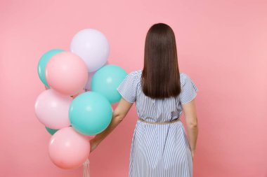 Dikiz parlak eğilimleri, pembe arka plan izole renkli hava balonları tutan mavi çizgili elbise giyen genç esmer kadın geri. Doğum günü tatil partisi, insanlar samimi duygular kavramı