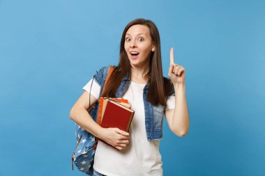 Genç kadın öğrenci sırt çantası işaret parmağı ile kopya alanı üzerinde şok ve üzerinde mavi arka plan izole okul kitapları holding yeni fikrim var. Lise Üniversite kavramı kolej eğitim