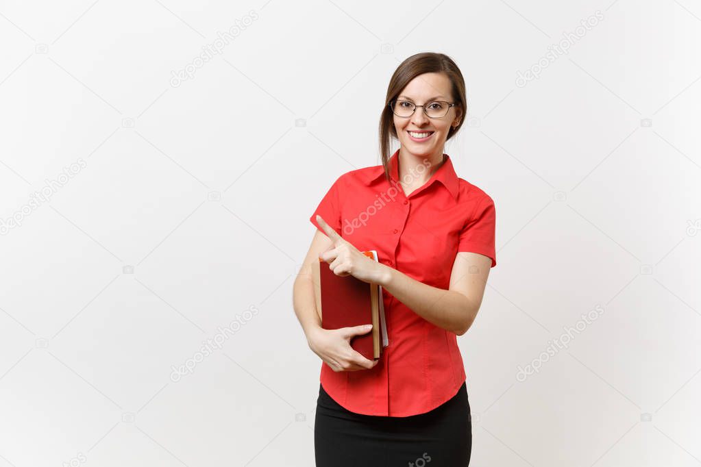 Portrait of young teacher woman in red shirt, skirt and glasses holding books, pointing finger aside on copy space isolated on white background. Education teaching in high school university concept