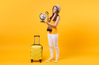 Seyahat etmek turist kadın yaz rahat kıyafetler, küre, sarı turuncu arka plan üzerinde izole bavul ile şapka. Hafta sonu kaçış üzerinde seyahat için yurt dışında seyahat yolcu. Hava uçuş yolculuk kavramı