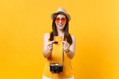 Turist kadın yaz rahat kıyafetler içinde eğlenceli, şapka, kredi kartı ile koruyucu gözlük, sarı turuncu arka plan üzerinde izole jest yaşasın. Hafta sonu kaçış üzerinde yurt dışı seyahat seyahat kız. Hava uçuş kavramı