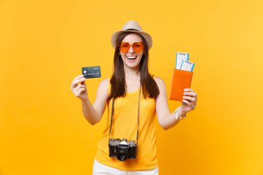 Mutlu turist kadın yaz rahat kıyafetler, kredi kartı, passport biletleri sarı turuncu arka plan üzerinde izole holding şapkası. Hafta sonu kaçış üzerinde seyahat için yurt dişi. Hava uçuş kavramı