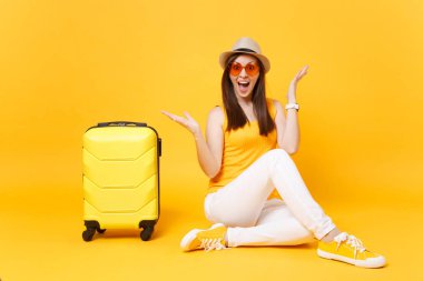 Seyahat etmek turist kadın yaz rahat kıyafetler, sarı turuncu arka plan üzerinde izole çanta şapka sit. Hafta sonu kaçış üzerinde seyahat için yurt kadın yolcu. Hava yolculuğu kavramı