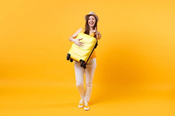 Traveler tourist woman in summer casual clothes, hat with suitcase isolated on yellow orange background. Female passenger traveling abroad to travel on weekends getaway. Air flight journey concept