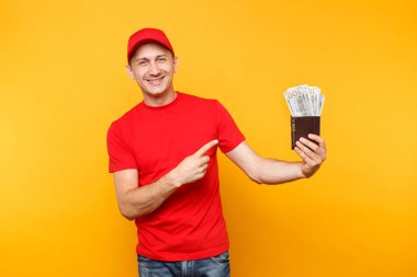 Teslimatçı sarı turuncu arka plan üzerinde izole kırmızı üniforma. Profesyonel erkek çalışan kap, t-shirt kurye veya paket çok dolar, nakit para tutan satıcısı. Hizmet anlayışı. Kopya alanı