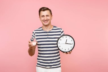 Çizgili tişört yuvarlak saat, holding beyaz adam mutlu portre saf su üzerinde gidişli pastel pembe arka plan izole cam temizleyin. İnsanlar sağlıklı yaşam konsepti. Zaman