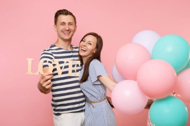 Portre çift aşk mektupları ahşap kelime tutun. Pastel pembe renkli hava Balonlu Parti kadın ve Doğum günü tatil kutluyor Mavi giysili adam. İnsanlar samimi duygular kavramı