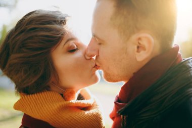 Genç romantik çift, kadın ve adam rahat kıyafetler sonbahar şehir parkta yürümek kadar kolay öpüşme açık havada güneşli bir günde kucaklayan kapalı gözlerle kapatın. Aşk ilişki aile yaşam tarzı kavramı