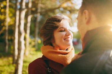 Kadın adamı rahat kıyafetler birbirine yürüyüş sonbahar Şehir Park açık havada güneşli bir günde bakarak kucaklayan gülümseyen genç romantik çift kapatın. Aşk ilişki aile yaşam tarzı kavramı