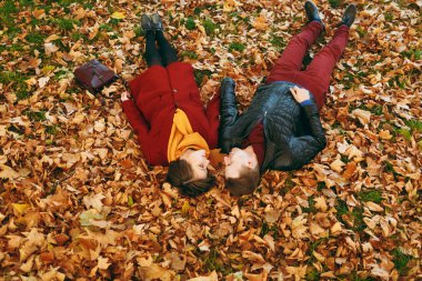 Genç romantik çift kadın ve erkek birbirlerine düşen yapraklar sonbaharda Şehir Park açık havada yatan bakarak elele rahat sıcak giysiler içinde seviyorum. Aşk ilişki aile yaşam tarzı kavramı
