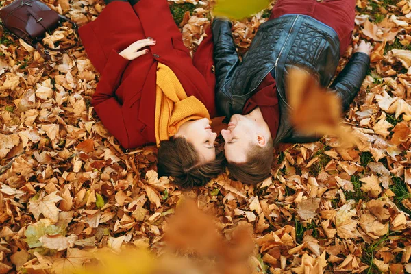 Üst görüntülemek genç gülümseyen çift aşk kadın ve erkek üzerinde düşen yapraklar sonbahar Şehir Parkı açık yalan el ele tutuşarak birbirlerine karşı karşıya kapalı gözlerle. Aşk ilişki aile yaşam tarzı kavramı