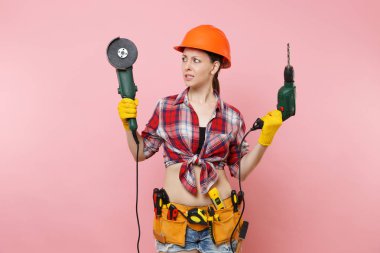 Enerji ev erkeği kadın eldiven, koruyucu turuncu kask, kit araçları kemer tam güç elektrikli matkap, pembe arka plan izole gördüm tutarak araçların eğlenceli. Kadın erkek iş. Yenileme kavramı