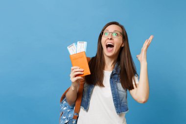 Çok memnun genç kadın ellerini tutun pasaport, yaymak sırt çantası öğrenci çığlık ile pas bilet üzerinde mavi arka plan izole yatılı heyecanlı. Yurt dışındaki üniversiteler eğitim. Hava seyahat uçuş