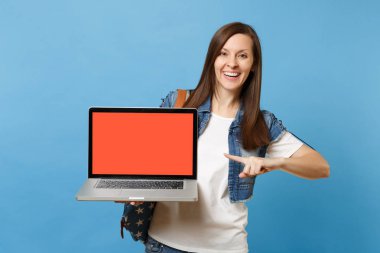 Sırt çantası laptop pc bilgisayarla iletişim izole mavi zemin üzerine boş siyah Boþ ekran işaret parmağı ile genç neşeli kadın öğrenci. Yüksek okulda eğitim. Kopya alanı reklam için