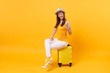 Seyahat etmek turist kadın yaz rahat kıyafetler, sarı turuncu arka plan üzerinde izole çanta şapka otur. Hafta sonu kaçış üzerinde seyahat için yurt kadın yolcu. Hava uçuş yolculuk kavramı