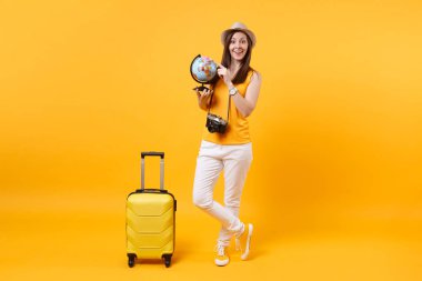 Seyahat etmek turist kadın yaz rahat kıyafetler, küre, sarı turuncu arka plan üzerinde izole bavul ile şapka. Hafta sonu kaçış üzerinde seyahat için yurt dışında seyahat yolcu. Hava uçuş yolculuk kavramı
